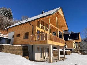 uma grande casa de madeira com um deque na neve em Nock Chalets em Afritz