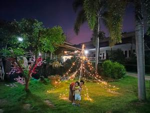 una familia parada frente a un árbol de Navidad en ระเบียงดอยโฮมสเตย์, en Wiang Pa Pao