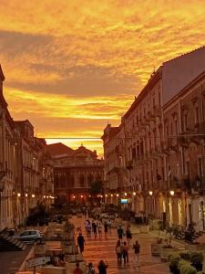 un groupe de personnes marchant dans une rue de la ville au coucher du soleil dans l'établissement Ivana B&B, à Catane