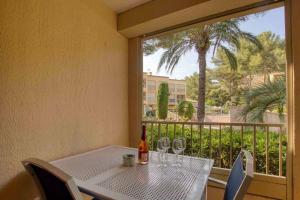 una mesa blanca con copas de vino en el balcón en Appartement piscine tennis accès privé plage Joïa en Sanary-sur-Mer