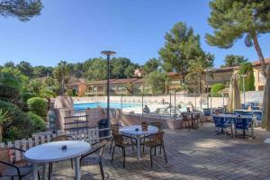 eine Terrasse mit Tischen und Stühlen neben einem Pool in der Unterkunft Appartement piscine/tennis accès privé plage in Sanary-sur-Mer