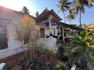 a white house with palm trees in front of it at Fatima Guest House in Baga