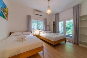 two beds in a room with two windows at Modern 2br 6 guets - ben gourion Blvd area in Tel Aviv