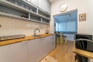 cocina con armarios blancos, fregadero y ventana en Modern 2br 6 guets - ben gourion Blvd area en Tel Aviv