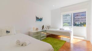 a white bedroom with two beds and a window at Charming Bessa Apartment by Unique Hosts in Porto
