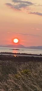 a sunset on the beach with the sun setting over the ocean at Glenashdale 28 A 1/R Boyd Street Largs KA308LE in Largs