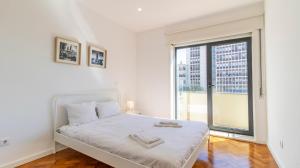 ポルトにあるCharming Boavista Apartment by Unique Hostsの白いベッドルーム(ベッド1台、大きな窓付)