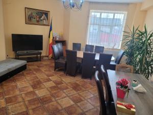 sala de estar con mesa, sillas y TV en Pensiunea Trei Brazi, en Târgu Ocna