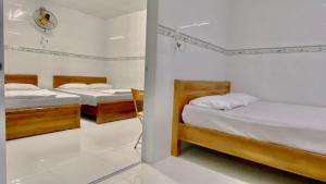 twee bedden in een kamer met witte muren bij Nhà Nghỉ MỸ THUẬN in Long Hai