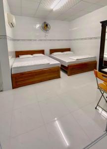 een kamer met twee bedden en een stoel erin bij Nhà Nghỉ MỸ THUẬN in Long Hai