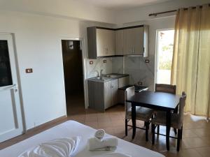 a room with a kitchen and a table and a bed at Vila Bashkim in Ksamil