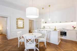 a white kitchen with a white table and chairs at MARIANNA'S OLD TOWN RESIDENCE in Ljubljana