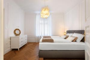 a white bedroom with a large bed and a chandelier at MARIANNA'S OLD TOWN RESIDENCE in Ljubljana