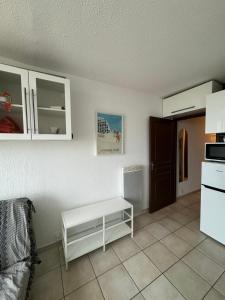 une cuisine avec des placards blancs et une table blanche dans l'établissement Belle vue sur mer avec place de parking, à La Grande Motte