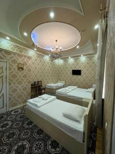 een kamer met 3 bedden en een kroonluchter bij Elite Hotel in Tasjkent