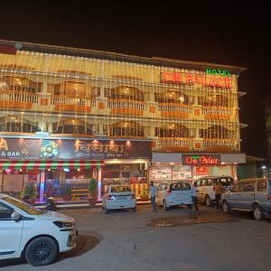 un bâtiment avec des voitures garées devant lui la nuit dans l'établissement Hotel Om Palace, à Lonavala