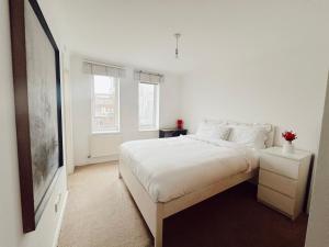 a white bedroom with a bed and a tv at Specious en-suite room - a cosy homestay close to Tower Bridge in London