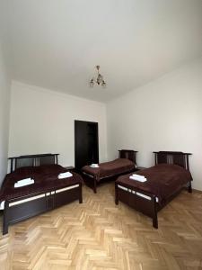 three beds in a room with wooden floors at Guest House - Tbilisi Center in Tbilisi City