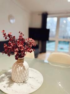 a white vase with red flowers in it on a table at Specious en-suite room - a cosy homestay close to Tower Bridge in London