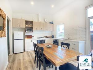 een keuken met een houten tafel en een witte koelkast bij The Purple Hen Hideaway Ramada Resort in Cowes