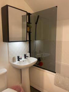 a bathroom with a sink and a shower with a mirror at Cosy Double Room in Dartford