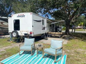 two chairs and a table in front of a trailer at Water Front Tracer RV by Glampers Camp in Port Charlotte