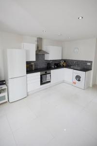 a white kitchen with white cabinets and appliances at Spire View Apartment*SO15 Sleeps 4-Secure Parking in Southampton