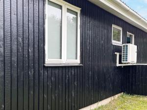 a black house with two windows and a air conditioner at 6 person holiday home in Oksb l in Vejers Strand