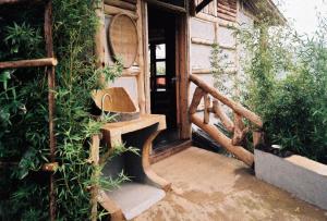 a house with a wooden stairway with a bench and plants at Bwindi My Home in Kinkizi