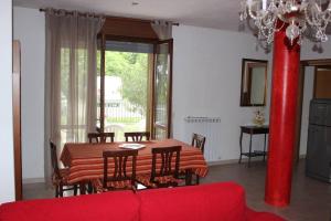 ein Wohnzimmer mit einem Tisch, Stühlen und einem roten Sofa in der Unterkunft Appartamento e giardino Perugia in Deruta