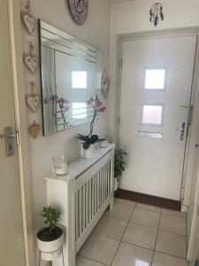 a hallway with a mirror and a door with potted plants at Cosy Double Room in Dartford