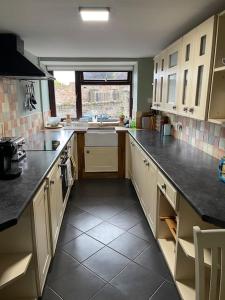 a kitchen with white cabinets and black counter tops at Stunning Cottage with Log Burner in Frosterley
