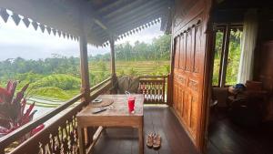 a room with a table on a balcony with a view at D'Ume Bendoel Homestay in Jatiluwih