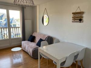 uma sala de estar com um sofá e uma mesa em T2, accès direct plage, proche thalasso em Cabourg