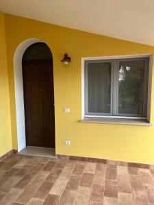 a yellow wall with a door and a window at Casa sul Conca in San Giovanni in Marignano