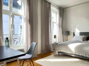 a bedroom with a bed and a desk and windows at Helle Altbauwohnung mit Balkon im Briller Viertel in Wuppertal
