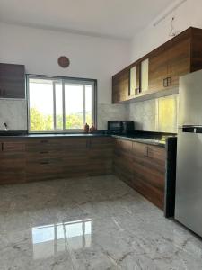 a kitchen with wooden cabinets and a stainless steel refrigerator at 2 bedroom beautiful shared villa with private kitchen and parking in Siolim