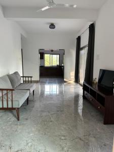 a living room with a couch and a television at 2 bedroom beautiful shared villa with private kitchen and parking in Siolim