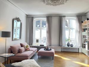 a living room with a pink couch and two windows at Helle Altbauwohnung mit Balkon im Briller Viertel in Wuppertal