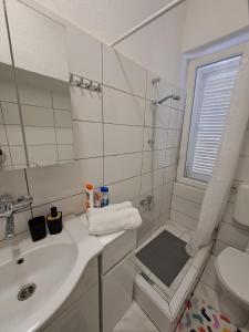 een witte badkamer met een wastafel en een douche bij Aida in Novi Vinodolski