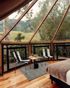 Cette chambre dispose d'une grande fenêtre avec deux chaises et une table. dans l'établissement Glamping Lumbre, à Salento