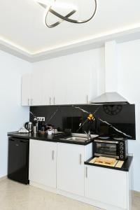 a kitchen with white cabinets and a black counter top at Sias Apartment in Alexandroupoli