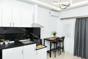 a kitchen with white cabinets and a table with chairs at Sias Apartment in Alexandroupoli