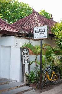 a sign in front of a building with a house at Cozy Bungalows in Gili Trawangan