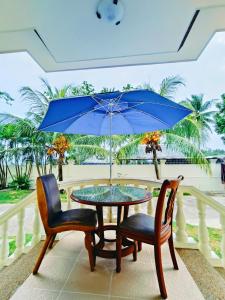 una mesa con 2 sillas y una sombrilla azul en Negros Haven Seaside Resort, en Jayugan