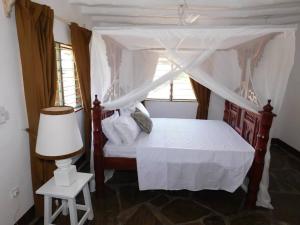 a bedroom with a canopy bed and a lamp at Holiday home in Malindi in Mambrui