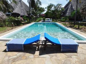 a swimming pool with two lounge chairs in front of it at Holiday home in Malindi in Mambrui