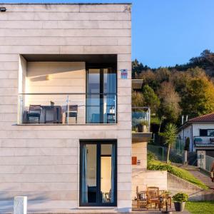 ein Haus mit Glastüren und einem Balkon in der Unterkunft Apartamentos Naredo in Villaviciosa