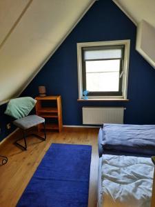 Dormitorio azul con cama y ventana en 't Wad, en Tzummarum