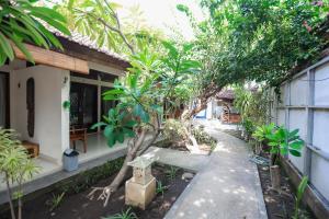 a garden in front of a house with trees at Cozy Bungalows in Gili Trawangan